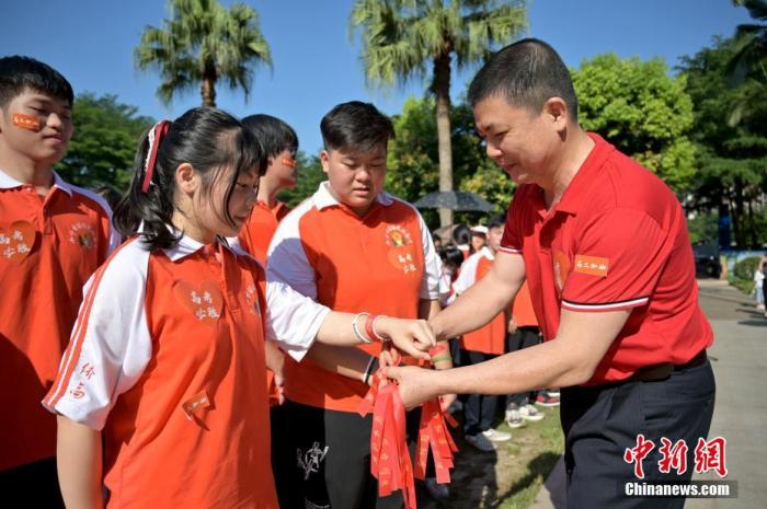 資料圖：廣西華僑實(shí)驗(yàn)高中的教師為高三學(xué)子系上紅絲帶，盼望學(xué)子高考必勝。 俞靖 攝